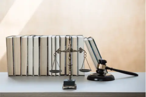 Waga sprawiedliwości, młotek sędziowski i stos książek prawniczych. Symbolika prawa i wymiaru sprawiedliwości, jakby z podręcznika 160 kk.