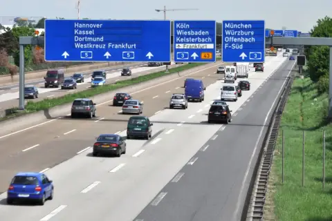 Autostrada w Niemczech z tablicami kierunkowymi do Kolonii, Frankfurtu i Monachium. Pytanie: czy w Niemczech są płatne autostrady?