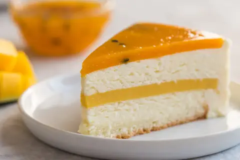 Pyszny tort mango z warstwami musu i galaretki, ozdobiony owocami. Idealny deser dla miłośników tropikalnych smaków.