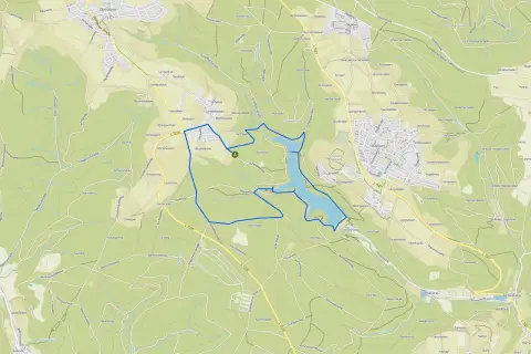 Der Herrenbachstausee mit seiner Kugelbahn-ähnlichen Uferlinie, eingebettet in grüne Hügel und Wälder.
