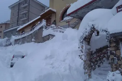 Neve alta a Scanno, quasi sepolta un'auto. L'arco in pietra, forse l'ingresso alla grotta dei colombi, è coperto di neve.