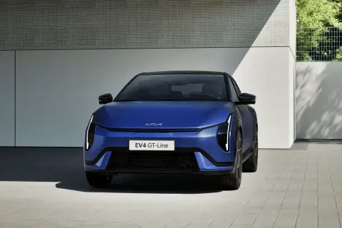Niebieski Kia EV4 GT-Line, elektryczny sedan, prezentuje się nowocześnie przed budynkiem.
