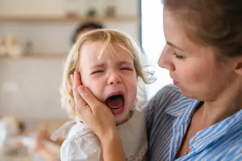 Mama pociesza płaczące dziecko, które przeżywa lęk separacyjny.