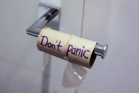 Pusta rolka po papierze toaletowym z napisem "Don't Panic" (Nie panikuj). Może to być metafora sytuacji, w której brakuje czegoś, ale nie ma powodu do zmartwień, jak np. w przypadku problemów żołądkowych, gdzie Tasectan mógłby pomóc.