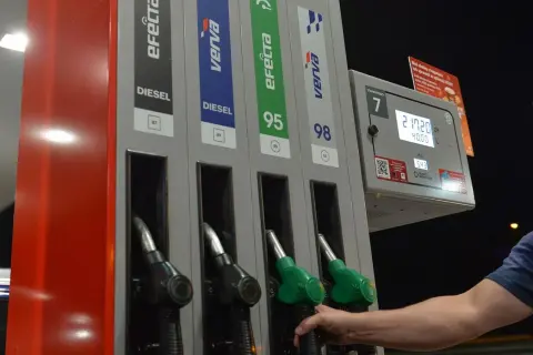 Dłoń sięga po dystrybutor z napisem DIESEL. Na stacji paliw można wybrać różne rodzaje paliwa, w tym diesel.