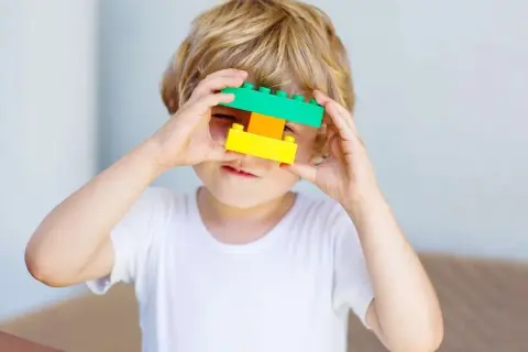 5 letnie dziecko bawi się klockami, tworząc z nich okulary.