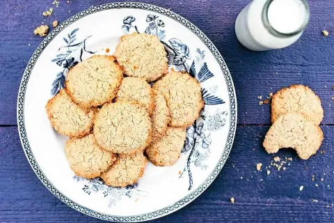 En tallrik med hembakade havrekakor, perfekt för ett enkelt havrekakor recept. En flaska mjölk står bredvid.