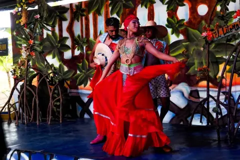 Dansare i färgglada dräkter uppträder på en scen med tropisk bakgrund, som påminner om Cali, Colombia.