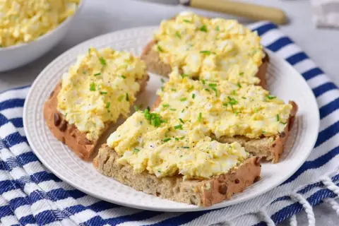 Pyszna pasta jajeczna z twarogiem na chlebie, posypana szczypiorkiem. Idealna na śniadanie lub przekąskę.