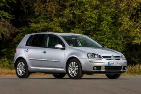Srebrny Volkswagen Golf 5 z 2004 roku zaparkowany na drodze, z zielonym lasem w tle.