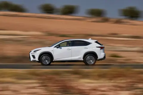 Biały suv Lexus NX 350h jedzie po pustynnej drodze, rozmywając krajobraz.