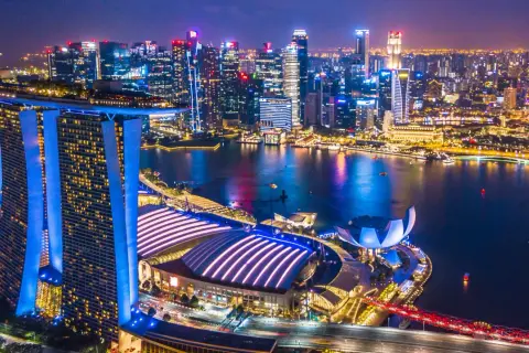 Nocny widok na Singapur z oświetlonymi drapaczami chmur i Marina Bay Sands. Miasto tętni życiem, a jego rozwój, jak singapur szczepienia, świadczy o postępie.