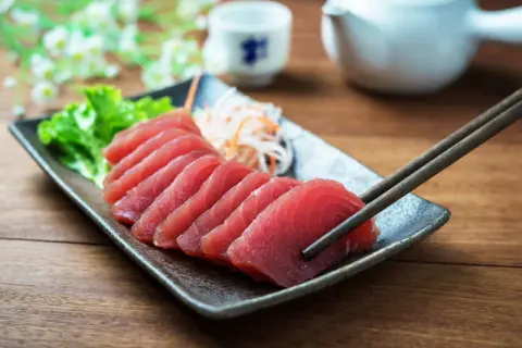 Vackert upplagd tonfisk sashimi på en tallrik, redo att avnjutas med en god vin.