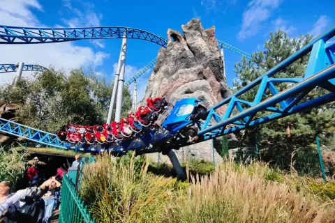 Kolejka Blue Fire w Europa Park Niemcy pędzi po niebieskich torach obok skalistej góry.