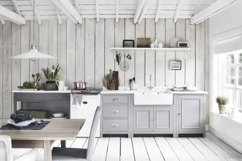 Ljust och luftigt kök med vit inredning inspiration. Träpaneler på väggar och tak, gråa skåp och en vit diskho.