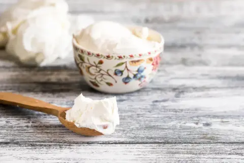 Cremiger Quark auf einem Holzlöffel und in einer Schale. Ja, ist Quark gesund und lecker!