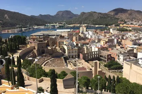 Vista panorámica de Cartagena, con el teatro romano y el castillo de la Concepción dominando el paisaje urbano y el puerto.