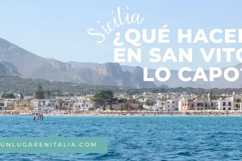 Vista de la playa de San Vito Lo Capo, Sicilia, con aguas azules y montañas al fondo.