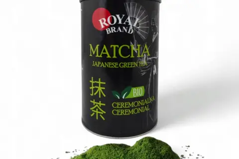 Czarna puszka z zieloną herbatą matcha Royal Brand i garść proszku matcha na białym tle.
