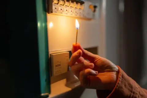 Mano con fiammifero acceso vicino al quadro elettrico, per capire cosa fare se salta la corrente.