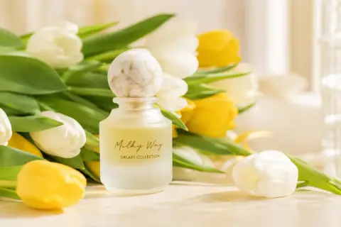 Eleganckie perfumy na prezent, otoczone bukietem białych i żółtych tulipanów. Czy to dobry omen, czy przesądy związane z podarunkiem?