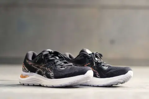 Scarpe da corsa Asics Gel Cumulus 23 nere con dettagli in bronzo e suola bianca, pronte per ogni avventura.