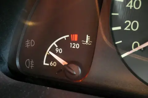 Le témoin de température moteur s'allume, indiquant une **cause surchauffe moteur essence**. Le thermomètre est proche de 120°C.