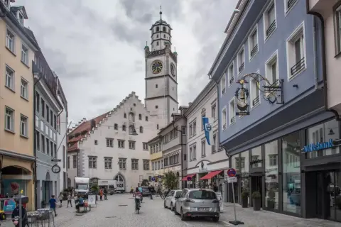 Der Blaserturm Ravensburg ragt über eine belebte Gasse mit Geschäften und Menschen.