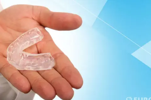 Mano che tiene un bite trasparente. Questo dispositivo, se usato correttamente, può aiutare a correggere la posizione dei denti.