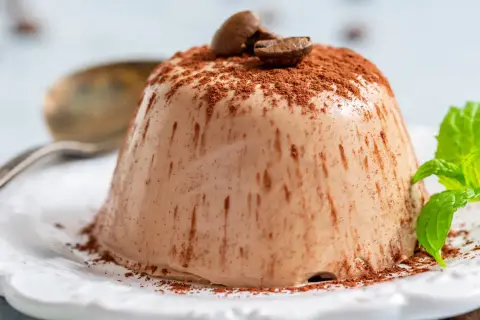 En krämig italiensk pannacotta, pudrad med kakao och toppad med kaffebönor. En frisk myntakvist ger en fin kontrast.