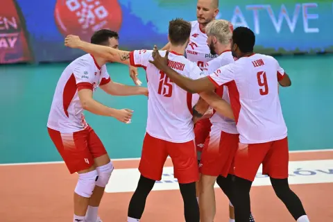 Siatkarze reprezentacji Polski w biało-czerwonych strojach świętują na boisku.