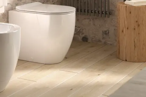 Bagno moderno con vaso e bidet bianchi su un caldo pavimento in pvc per bagno, opinioni positive per questo stile.
