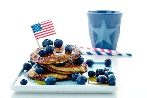 En stapel pannkakor med blåbär och en amerikansk flagga. Perfekt för att frysa pannkakor och njuta av en amerikansk frukost.