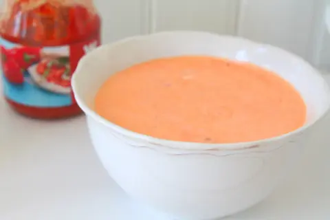 En skål med krämig, kall sås till grillad kyckling, gjord på crème fraiche. En burk med tomatsås skymtar i bakgrunden.