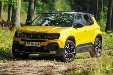 Żółty Jeep Avenger na leśnej drodze. Wiele pozytywnych jeep avenger opinie potwierdza jego miejski charakter i stylowy wygląd.