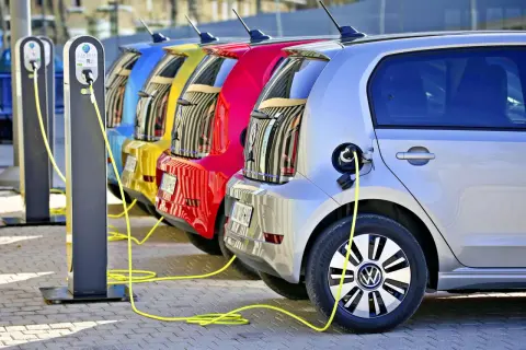 Kolorowe samochody elektryczne w Polsce ładowane na stacji.