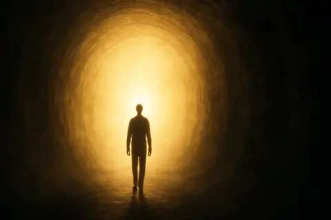 Silueta de una persona caminando hacia una luz brillante en un túnel, evocando experiencias cercanas a la muerte.