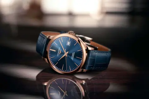 Elegancki zegarek damski rose gold z granatową tarczą i skórzanym paskiem, odbijający się w błyszczącej powierzchni.