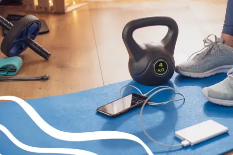 Gotowy sprzęt do treningu: hantle, gumy, rolka, mata, telefon i powerbank. Idealne warunki do cardio w domu.