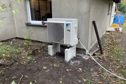Nowoczesna pompa ciepła woda woda Daikin, zamontowana na zewnątrz budynku, gotowa do pracy.