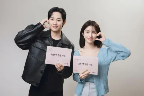 Jung Hae In und seine Kollegin halten Drehbücher für "A Love So Beautiful" und lächeln.