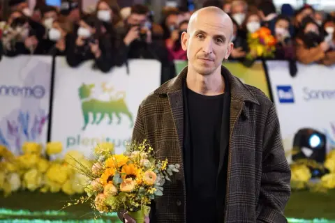 Un uomo con un mazzo di fiori, forse pensando ai testi di Fabrizio De André nella sua ora di libertà.
