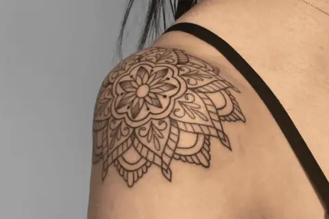 Mandala-Tattoo auf der Schulter einer Frau, detailliert und filigran gezeichnet.