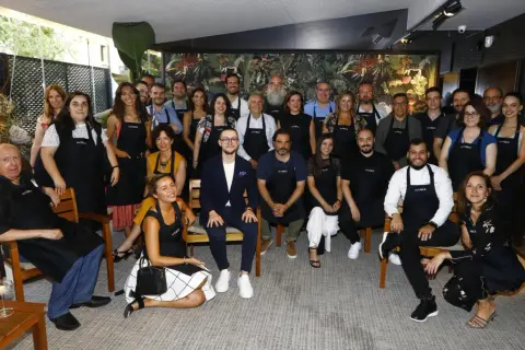 Grupo diverso posa con delantales "es.table Zaragoza" en un evento.