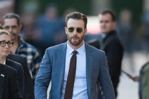 Chris Evans trägt einen blauen Anzug mit einem hellblauen Hemd und einer braunen Krawatte. Ein brauner Anzug kombiniert mit dieser Krawatte wäre auch stilvoll.