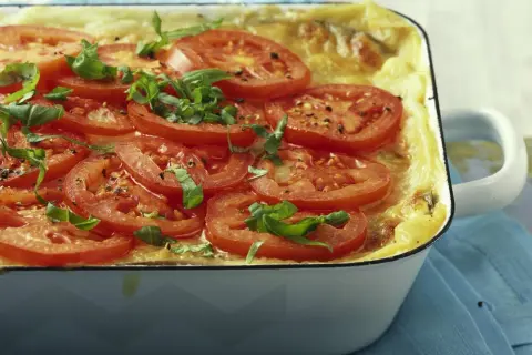 Herzhafte auberginen lasagne, überbacken mit Tomatenscheiben und frischem Basilikum, duftet verführerisch.