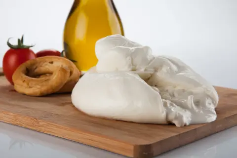 La burrata, un tesoro cremoso, si presenta su un tagliere con pomodorini, taralli e olio d'oliva.