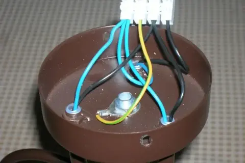 Brązowa podsufitka lampy z widocznymi przewodami: 3 kable z sufitu, 2 w lampie. Połączenia elektryczne w toku.