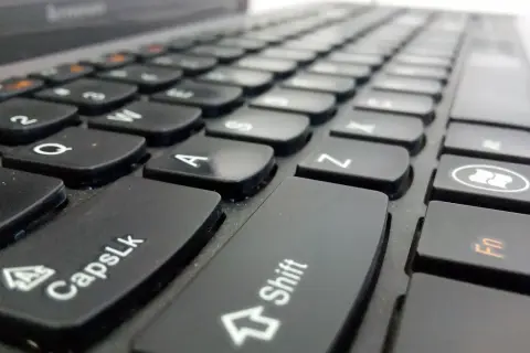 Primer plano de un teclado de portátil. La tecla Shift está en el centro, lista para escribir en mayúsculas.
