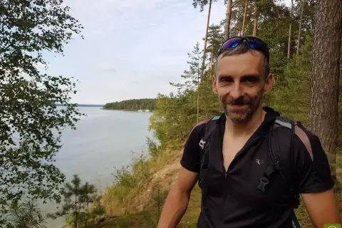 Uśmiechnięty rowerzysta na tle malowniczego zalewu sulejowskiego. Trasa rowerowa wokół zalewu sulejowskiego oferuje piękne widoki.